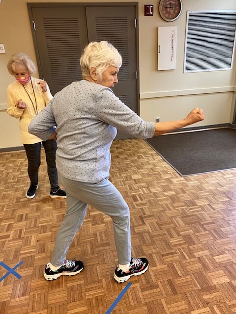 A woman practicing self-defense motions, improving balance along the way
